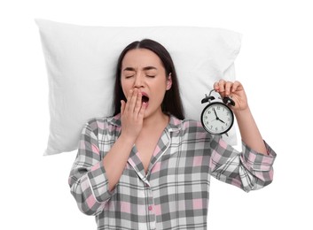 Photo of Tired young woman with alarm clock and pillow yawning on white background. Insomnia problem