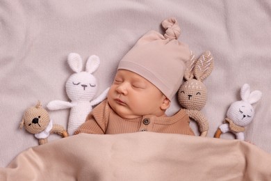 Cute newborn baby sleeping with toys in bed, top view