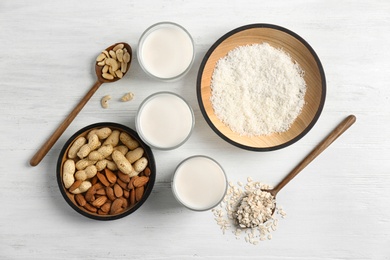 Glasses with different types of milk and ingredients on wooden background