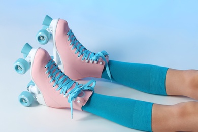 Woman with vintage roller skates on color background, closeup