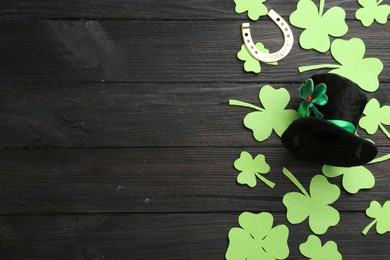 Photo of Leprechaun's hat and St. Patrick's day decor on black wooden background, flat lay. Space for text