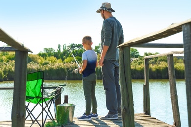 Father and son fishing together on sunny day