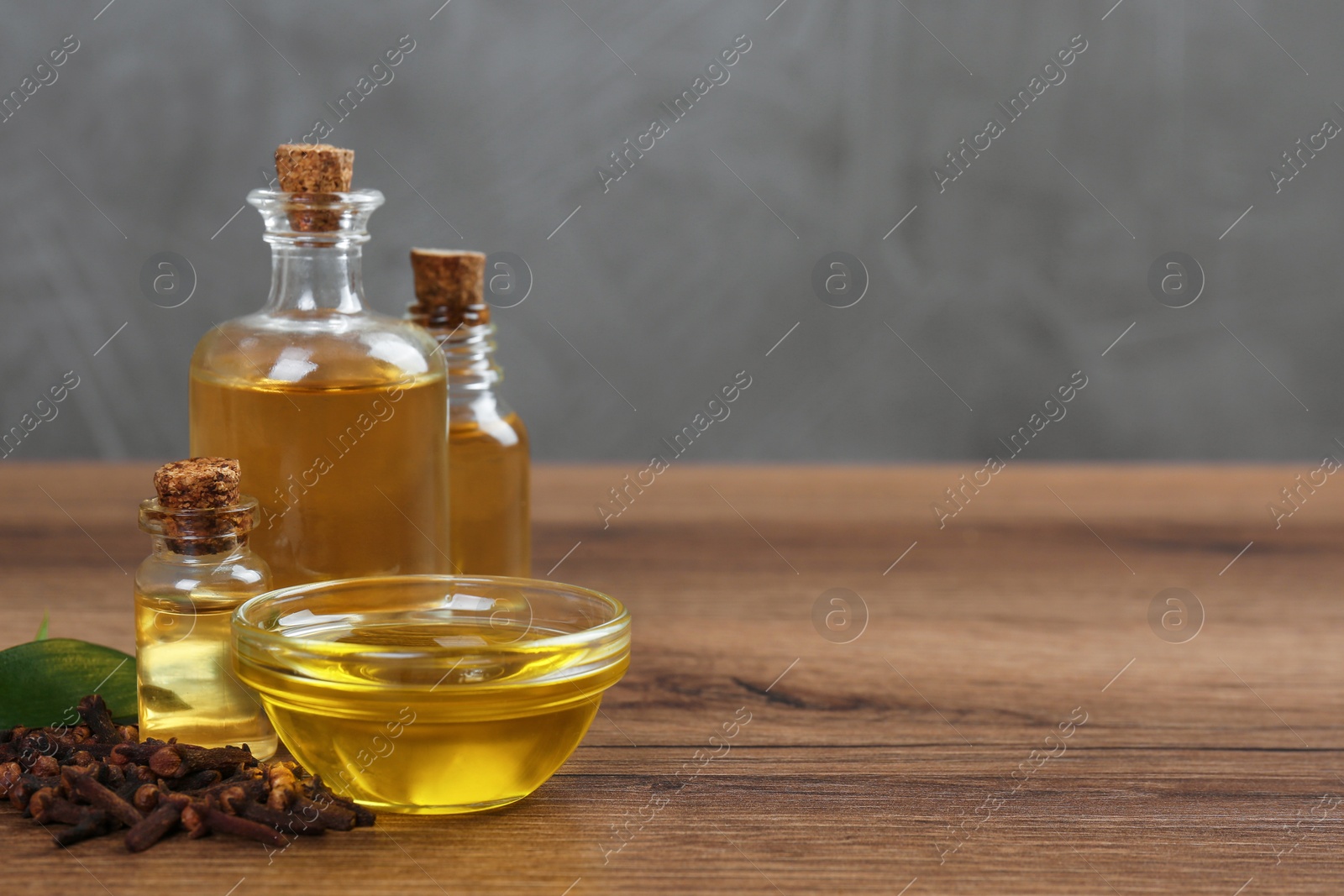 Photo of Essential oil and dried cloves on wooden table. Space for text