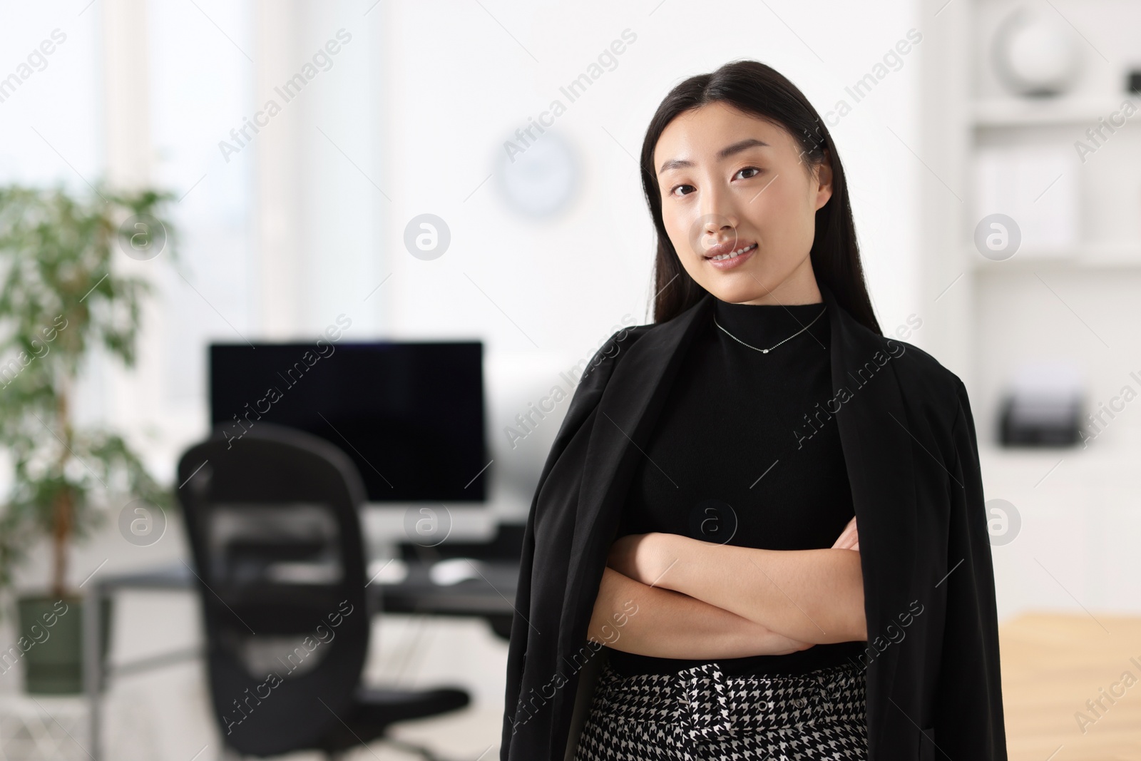 Photo of Portrait of smiling businesswoman with crossed arms in office. Space for text