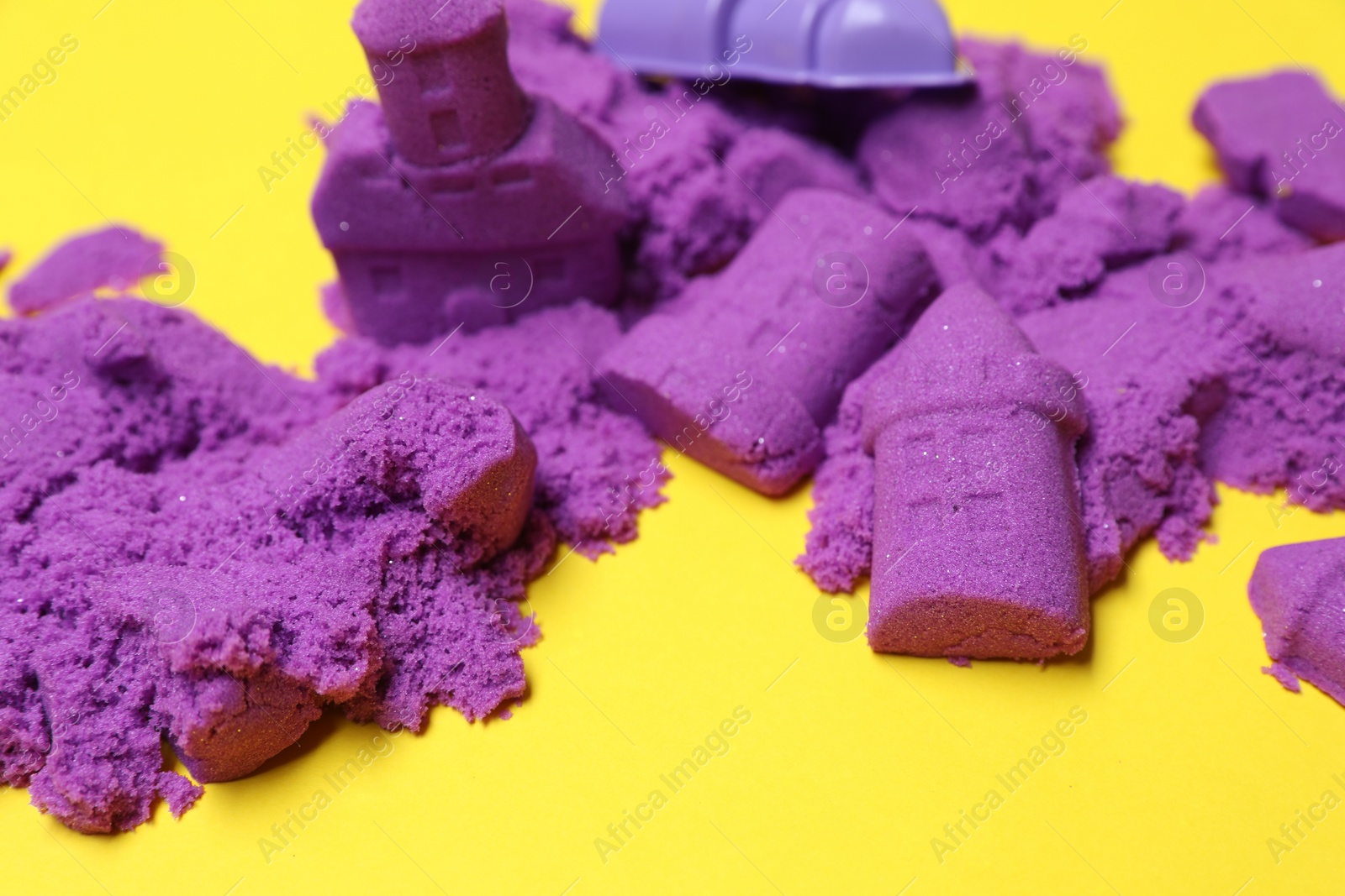 Photo of Bright kinetic sand on yellow background, closeup
