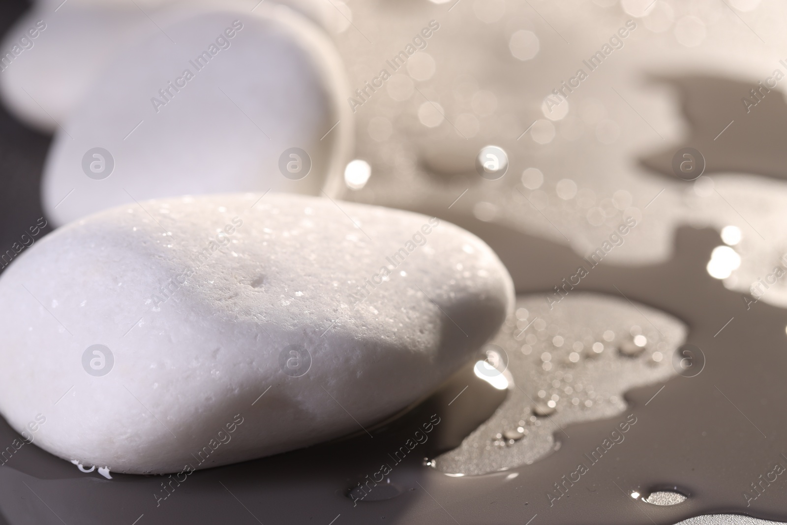 Photo of White spa stones with water drops on grey background, closeup