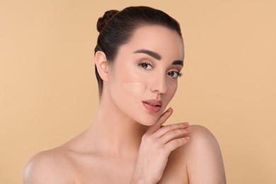 Woman with swatch of foundation on face against beige background