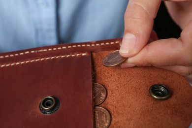 Photo of Young woman putting coin into wallet, closeup