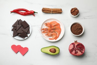 Photo of Natural aphrodisiac. Different products and paper hearts on white marble table, flat lay