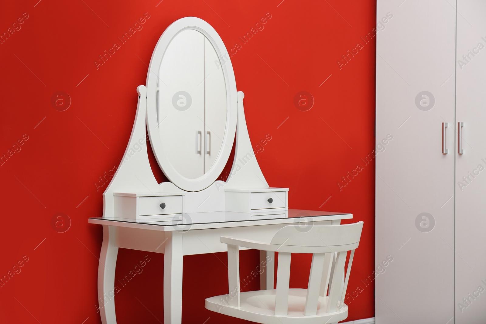 Photo of Elegant dressing room interior with makeup table near red wall