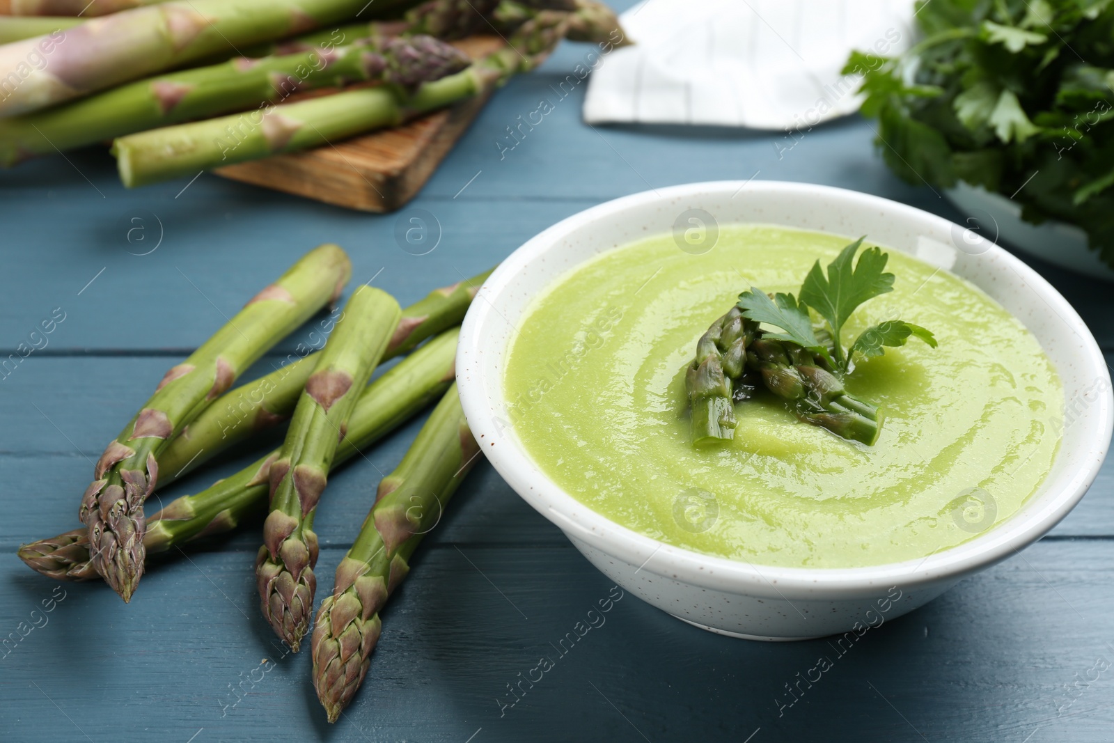 Photo of Delicious asparagus soup served on blue wooden table