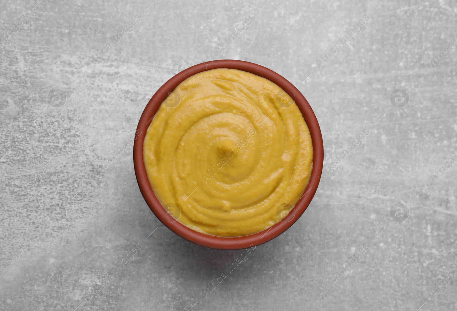 Photo of Bowl with delicious mustard on light grey table, top view