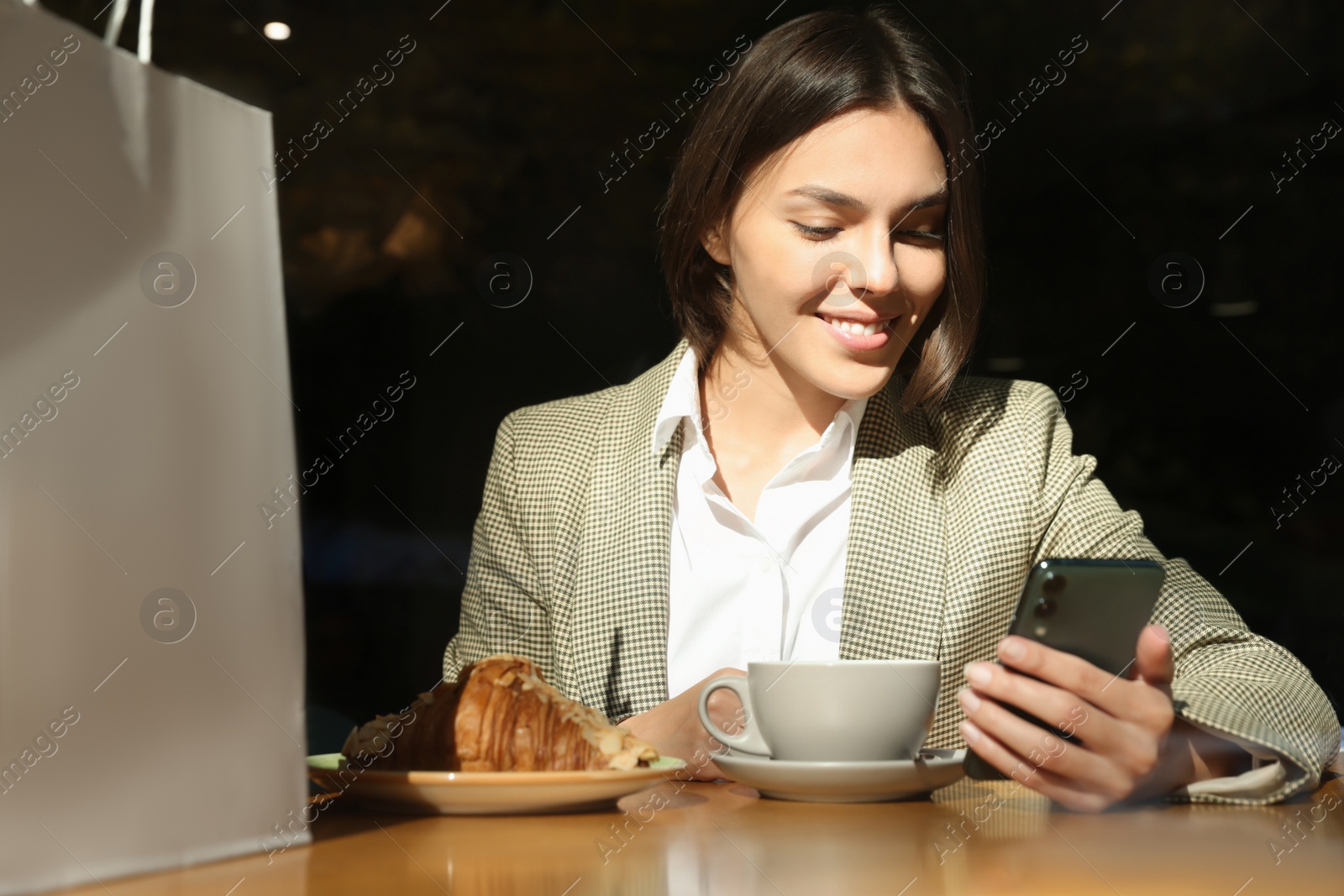 Photo of Special Promotion. Happy young woman using smartphone at table in cafe