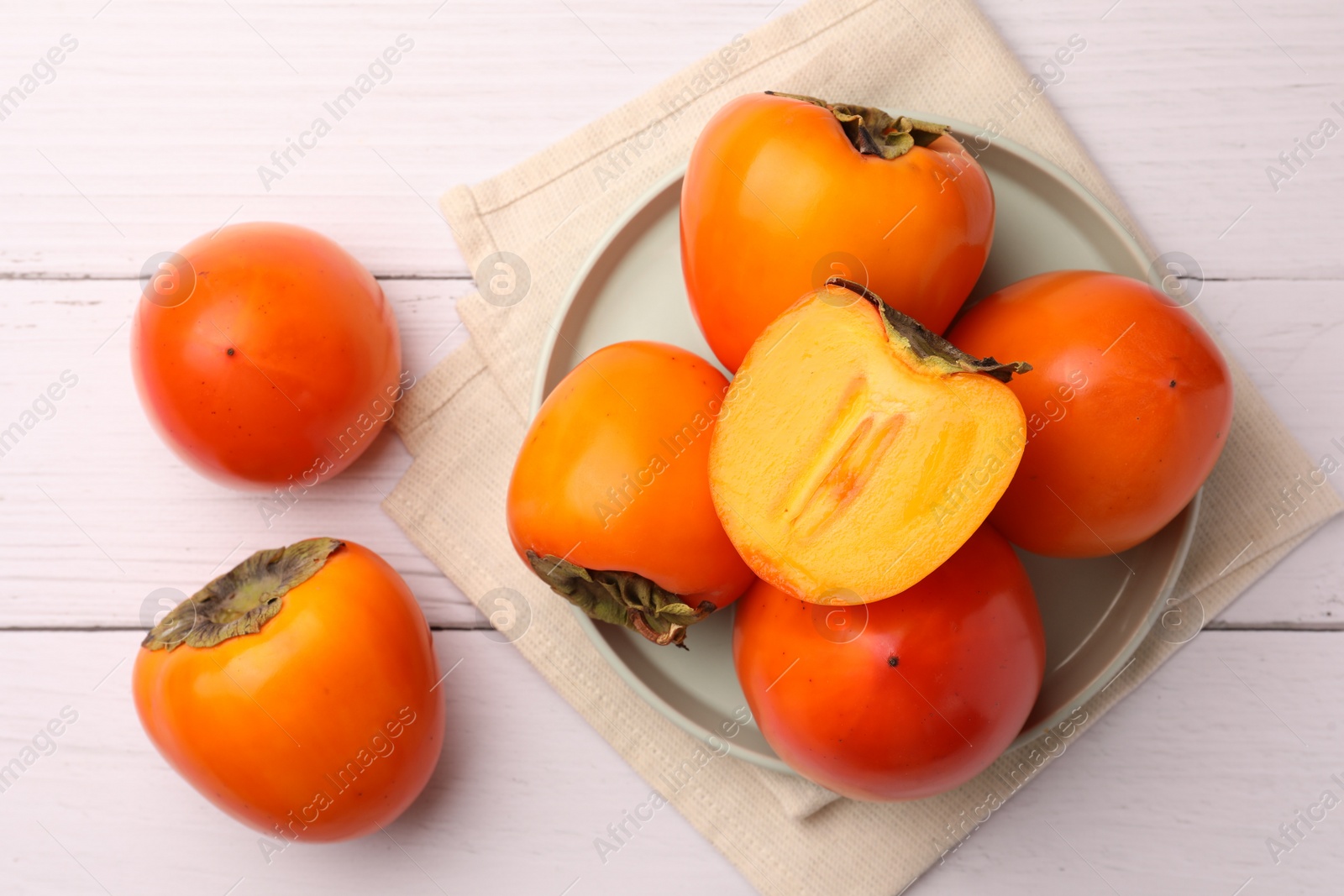 Photo of Delicious ripe juicy persimmons on white wooden table, flat lay