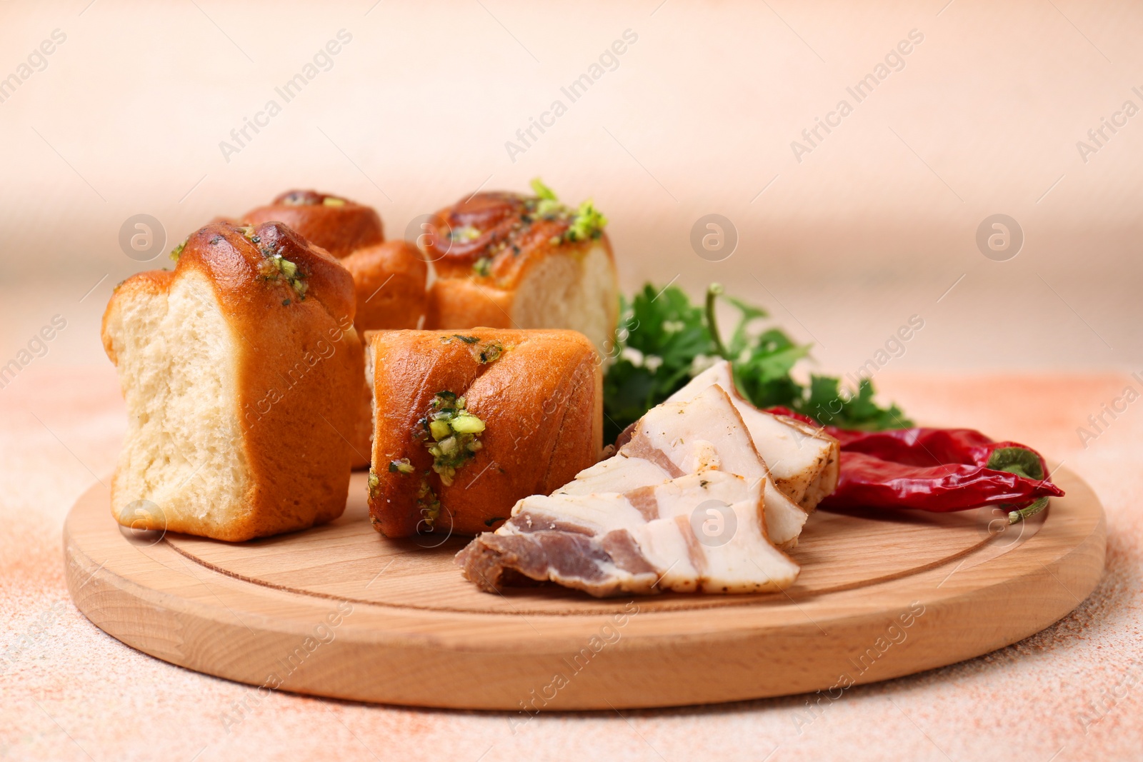 Photo of Delicious pampushky (buns with garlic), salo, peppers and parsley on color textured table