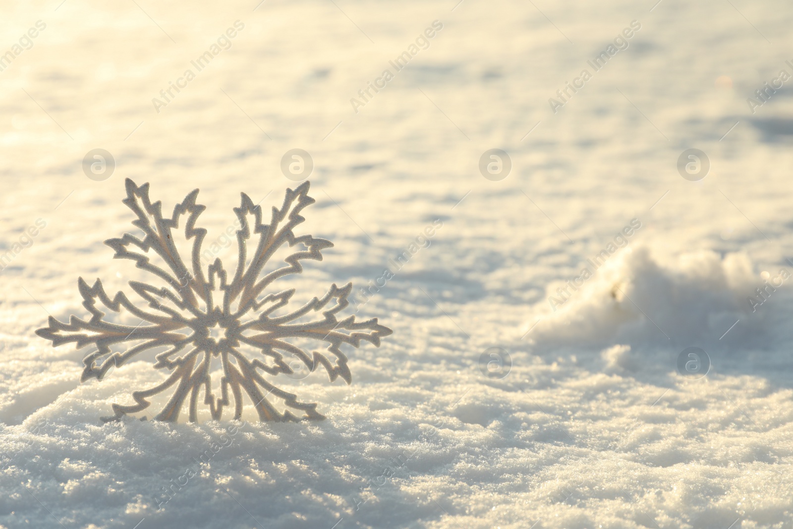 Photo of Beautiful decorative snowflake in white snow, outdoors. Space for text