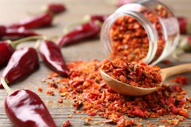 Chili pepper flakes and pods on wooden table, closeup. Space for text