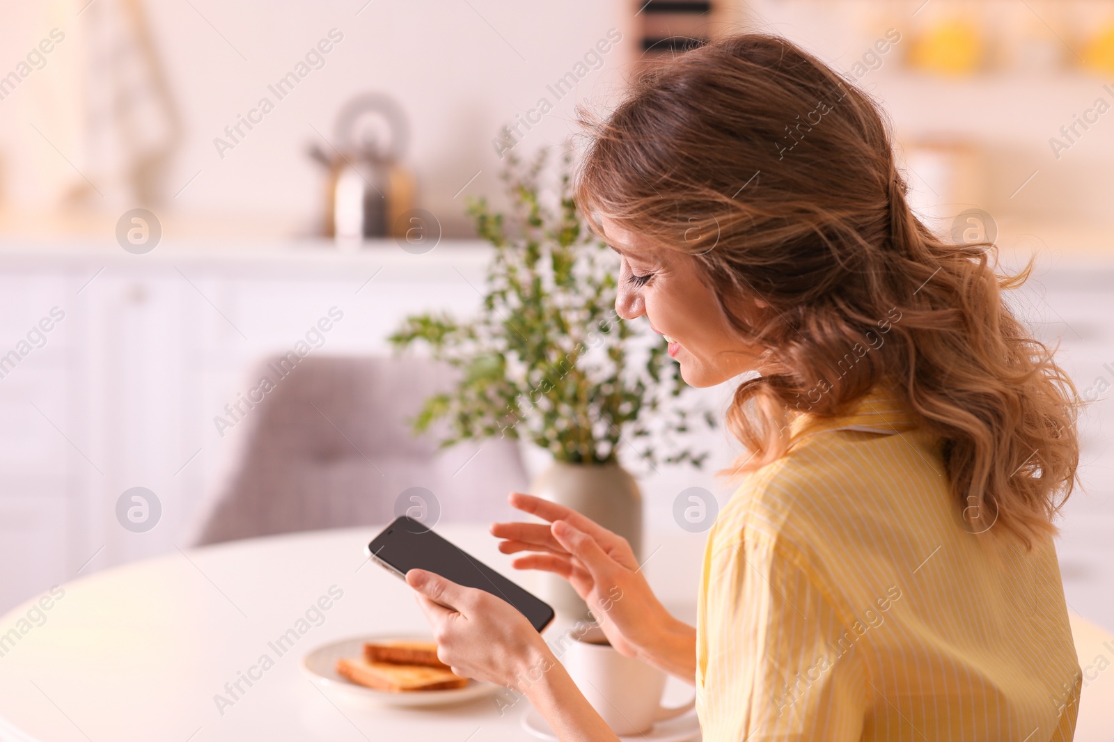 Photo of Beautiful young woman with smartphone relaxing at home. Weekend morning