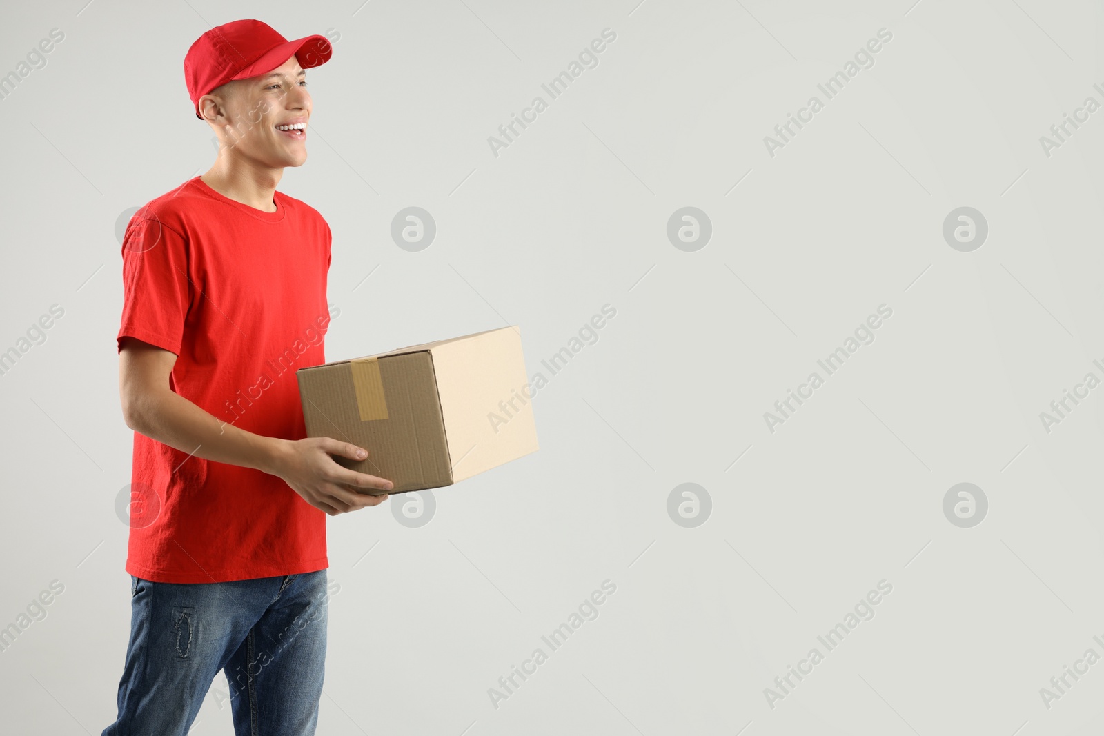 Photo of Happy courier with parcel on light grey background. Space for text