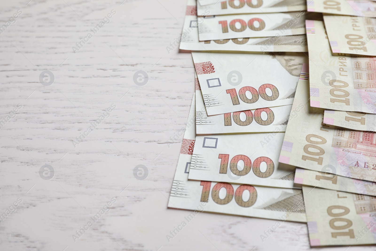Photo of Ukrainian money on white wooden background, closeup. Space for text