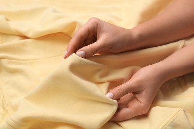 Photo of Woman touching soft yellow fabric, closeup view