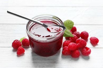 Image of Sweet raspberry jam and fresh berries on white wooden table