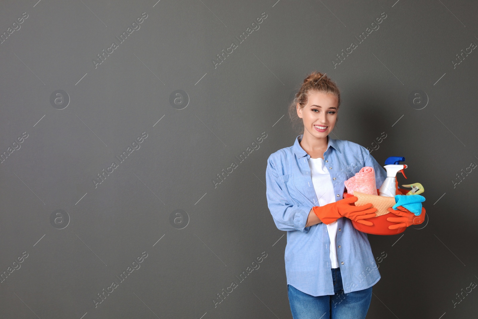 Photo of Woman with cleaning supplies on grey background