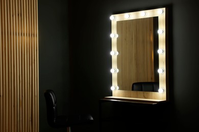 Beautiful mirror with light bulbs and chair in makeup room