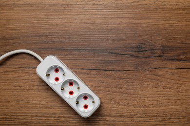 Photo of Extension cord on wooden floor, top view with space for text. Electrician's equipment