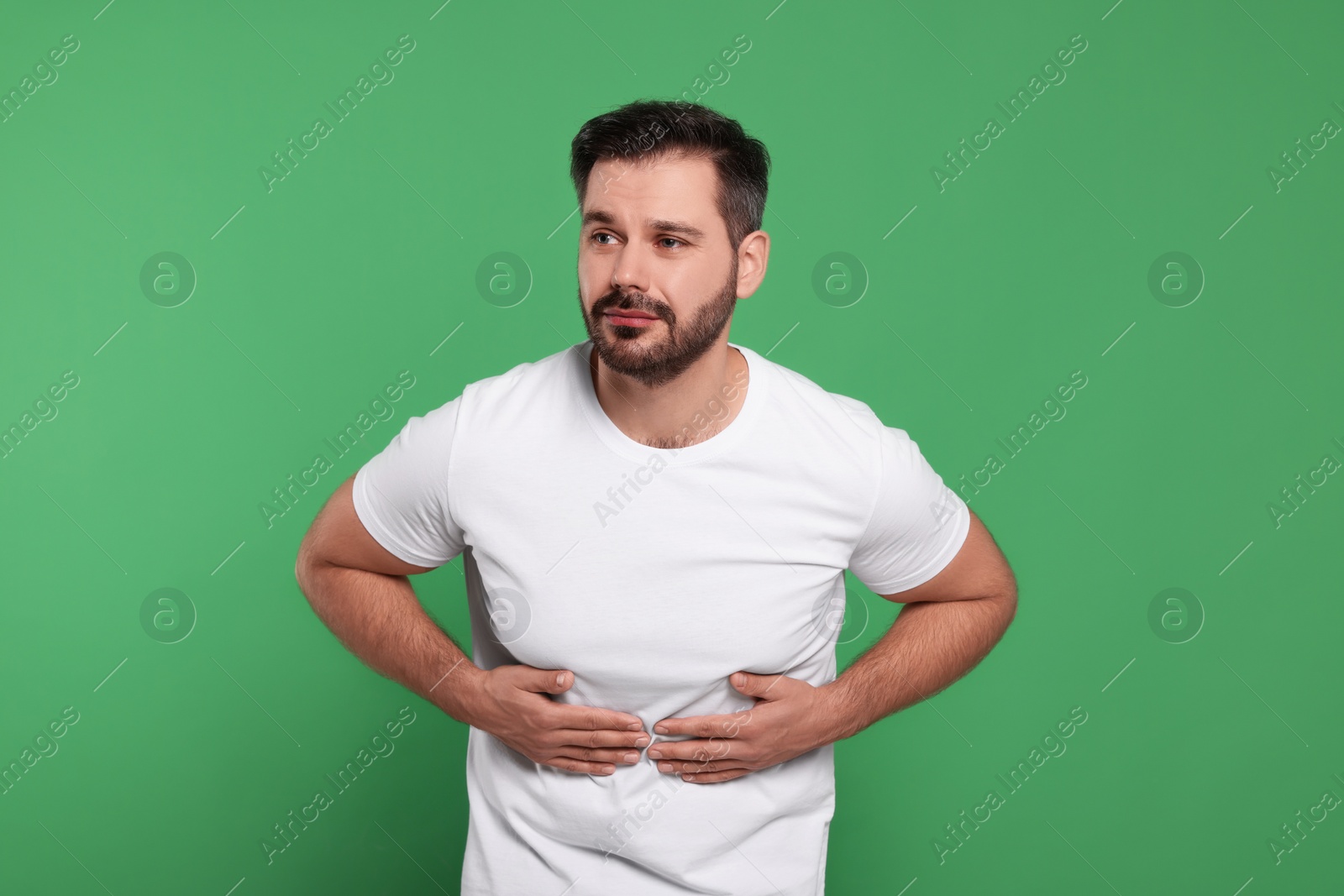 Photo of Man suffering from stomach pain on green background