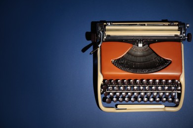 Photo of Vintage typewriter on dark blue background, top view. Space for text