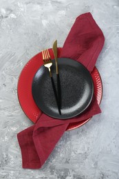 Clean plates, cutlery and napkin on gray textured table, top view