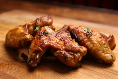 Delicious grilled chicken wings on wooden board, closeup