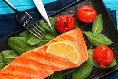 Photo of Tasty grilled salmon with tomatoes, spinach and lemon served on table, top view