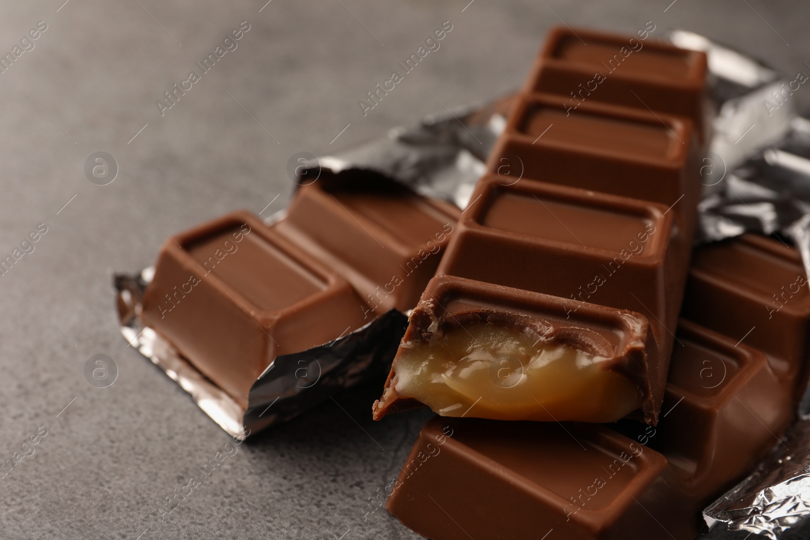 Photo of Tasty chocolate bars on grey table, closeup. Space for text