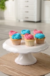 Photo of Delicious cupcakes with bright cream on wooden table indoors