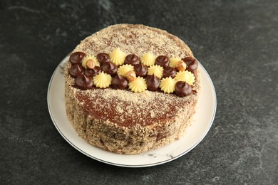 Photo of Delicious Kyiv Cake with cream and hazelnuts on black table