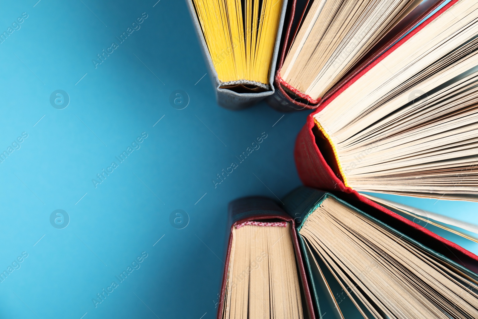 Photo of Hardcover books on light blue background, flat lay. Space for text