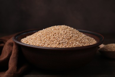 Dry wheat groats in bowl on table, closeup