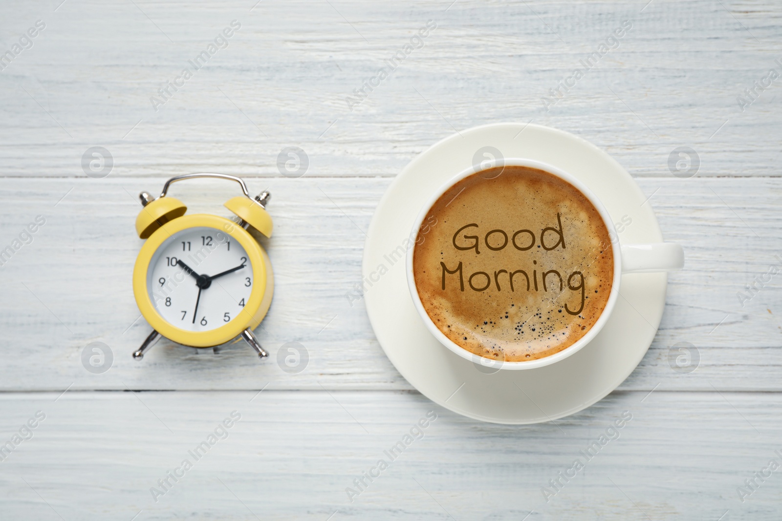 Image of Cup of aromatic coffee and alarm clock on white wooden table, flat lay. Good morning