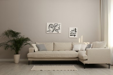 Photo of Stylish living room interior with modern comfortable sofa, plant and pictures