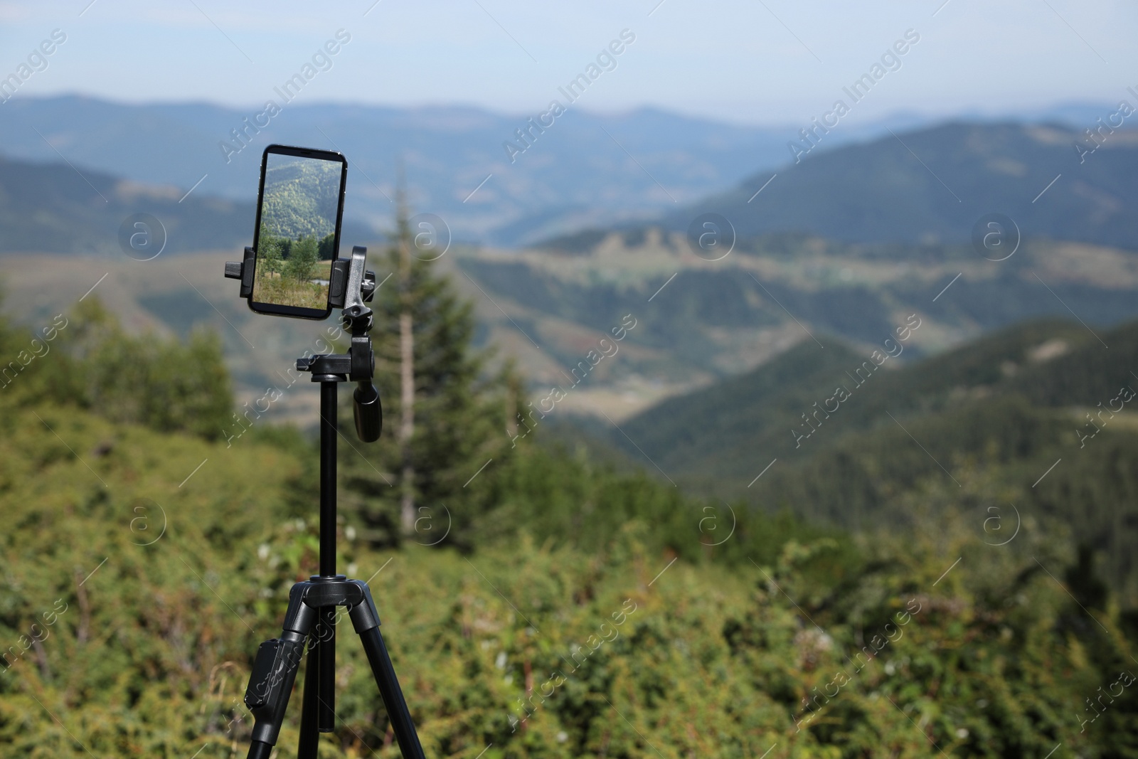 Photo of Taking video with modern phone on tripod in mountains