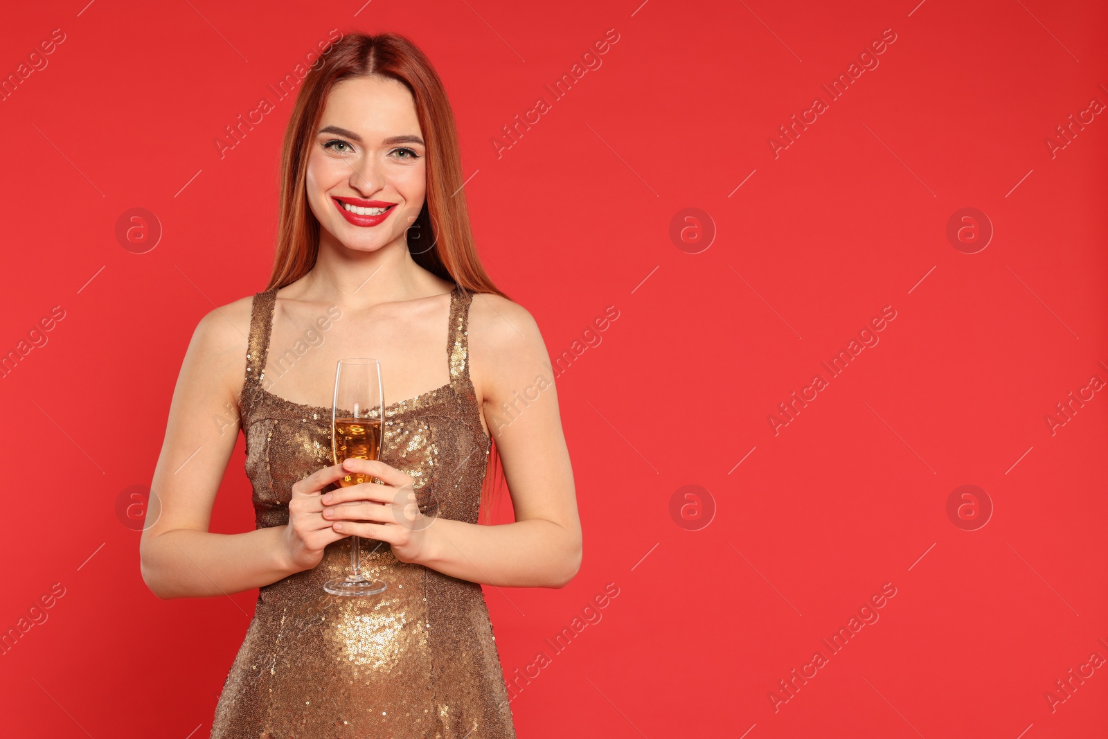 Photo of Young woman in dress with glass of wine on red background, space for text