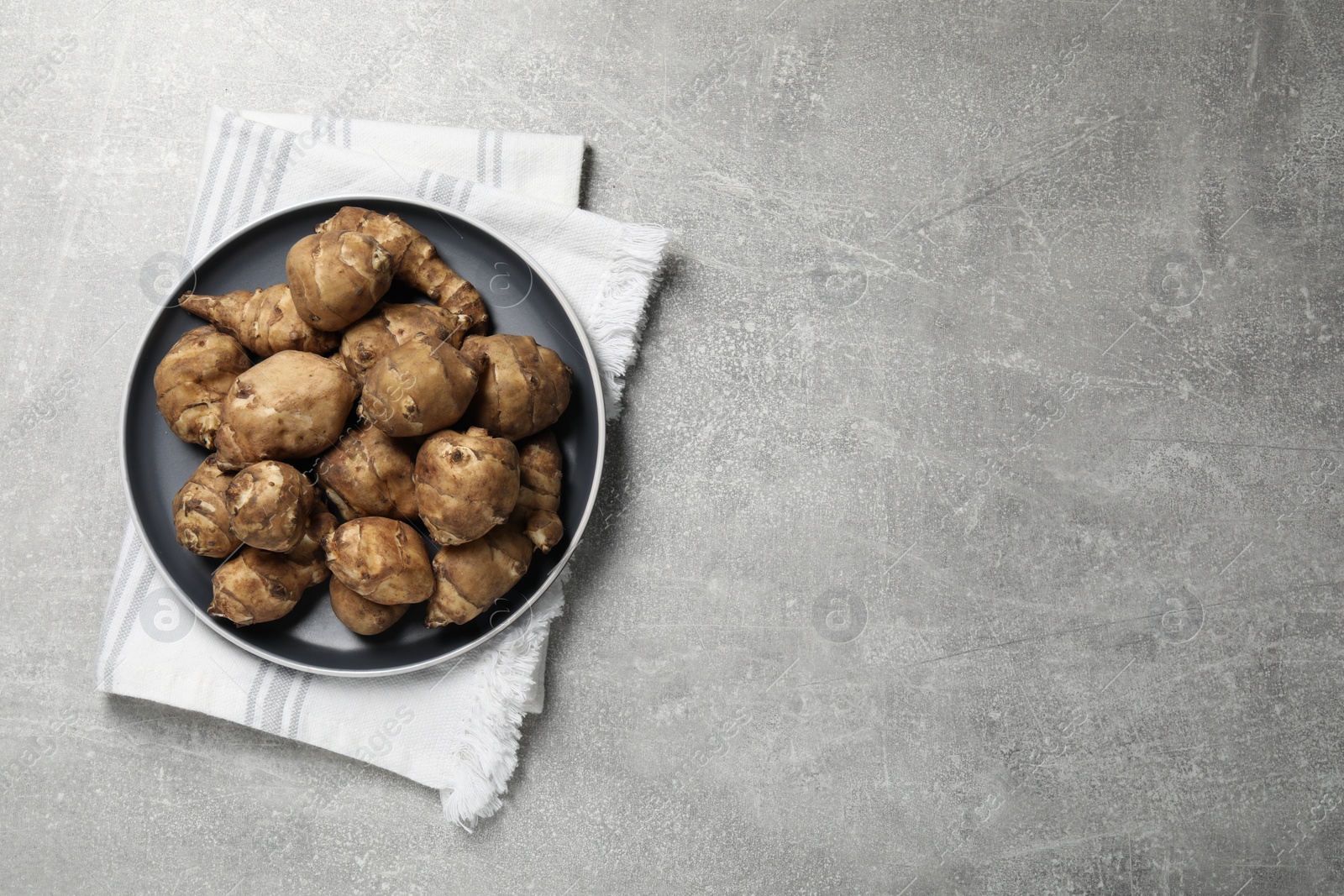 Photo of Jerusalem artichokes on light grey table, top view. Space for text