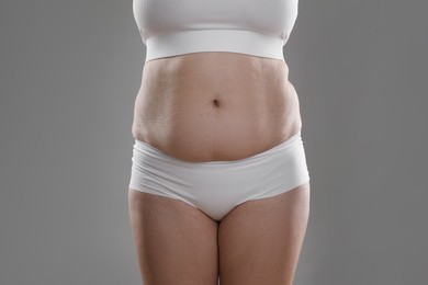 Photo of Woman with excessive belly fat on grey background, closeup. Overweight problem