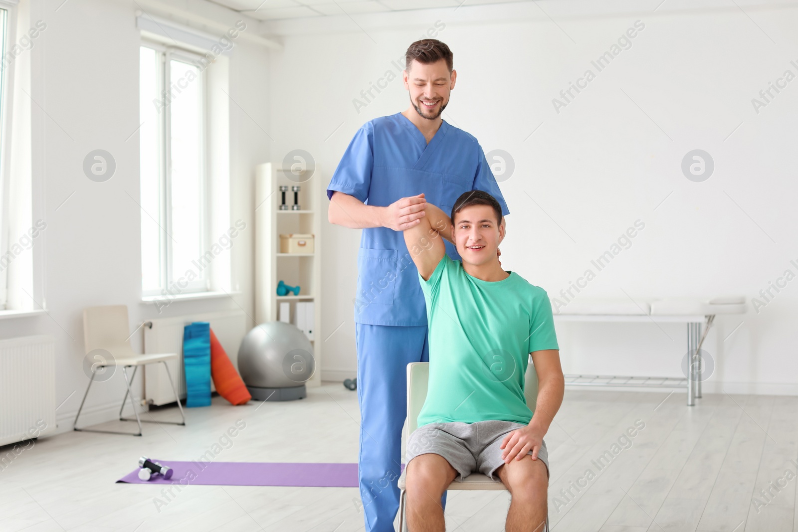 Photo of Physiotherapist working with male patient in clinic