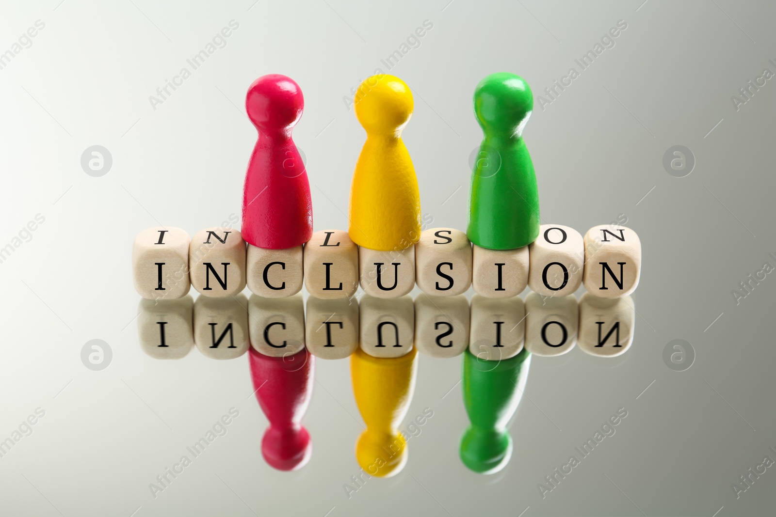 Photo of Colorful pawns and wooden cubes with word Inclusion on white background