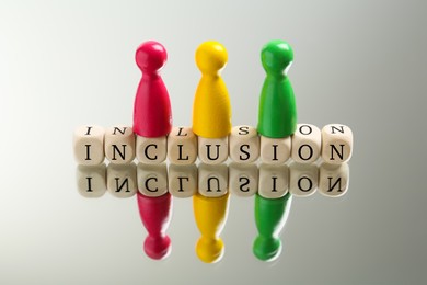 Photo of Colorful pawns and wooden cubes with word Inclusion on white background