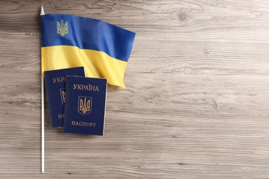 Photo of Ukrainian internal passports with national flag on wooden background, flat lay. Space for text