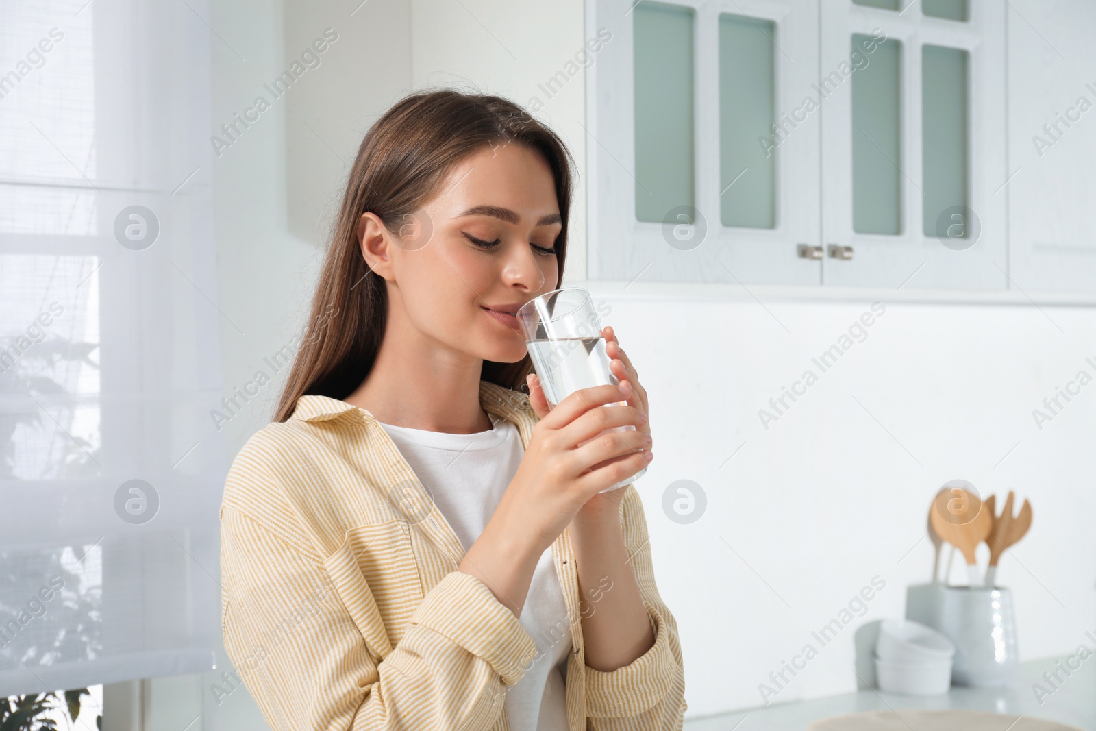 Photo of Woman drinking tap water from glass in kitchen